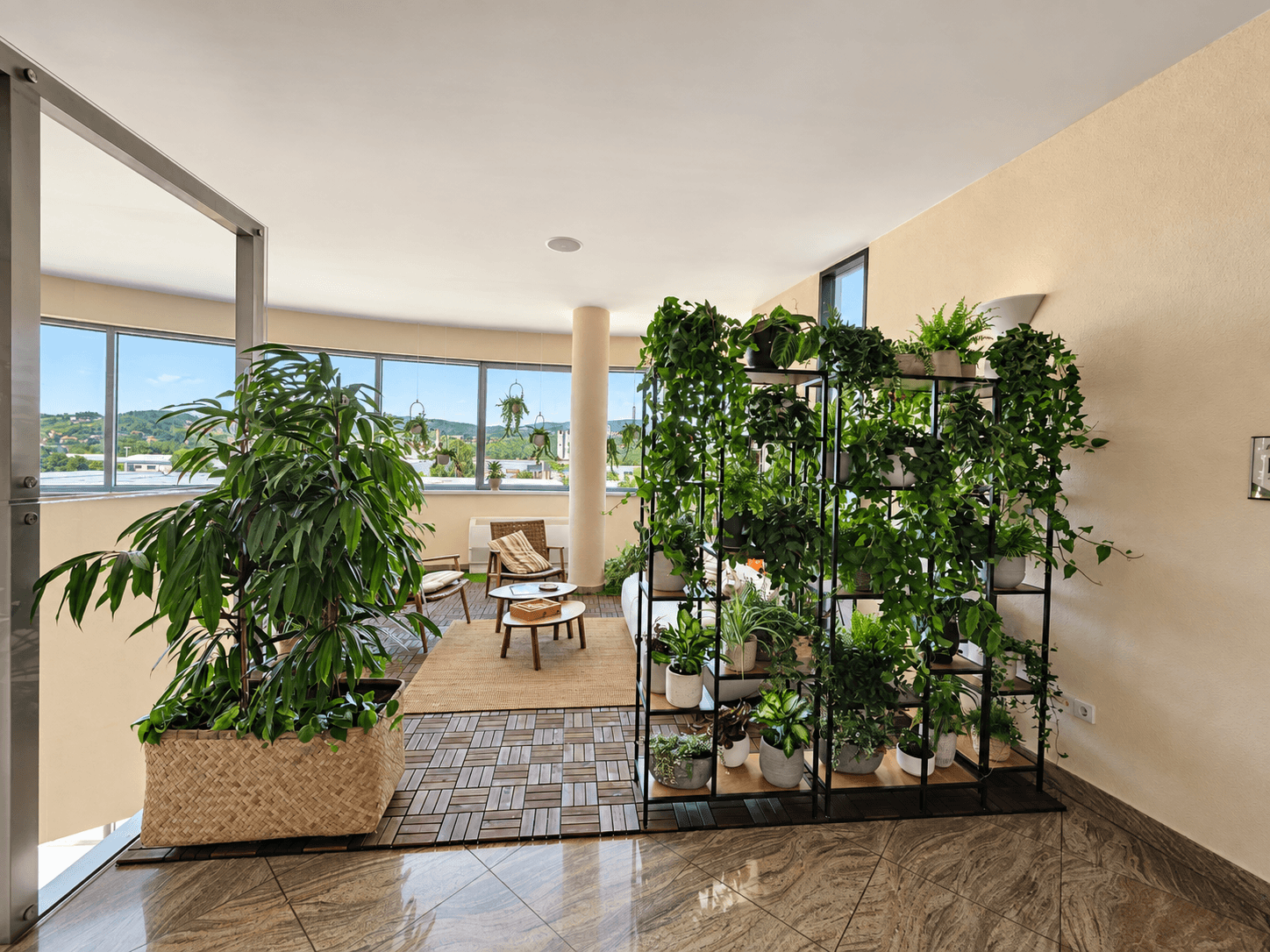 A green corner to unwind A seating area surrounded by tall plants and green screens beside large windows